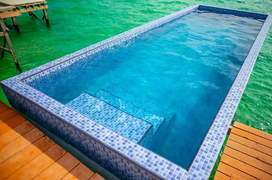 Private blue mosaic plunge pool built into the wooden deck over the clear turquoise ocean at the Family Deluxe room, Turtle Seaweed Resort.